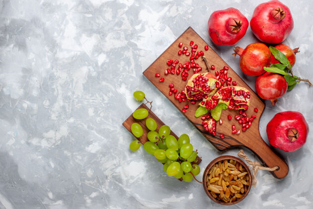 营养白色书桌上的红色石榴 新鲜多汁的水果和葡萄果汁饮食苹果