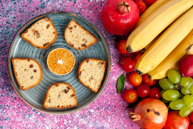 醇香的顶视图新鲜水果组成五颜六色的水果与美味的切片蛋糕在粉红色的桌子上桌子甜的饼干