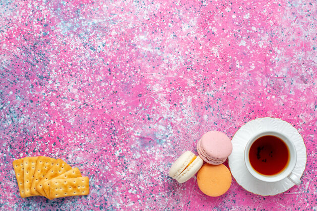 庆典在粉红色的桌子上可以看到一杯茶 里面放着法国马卡龙和饼干饼干顶部生的