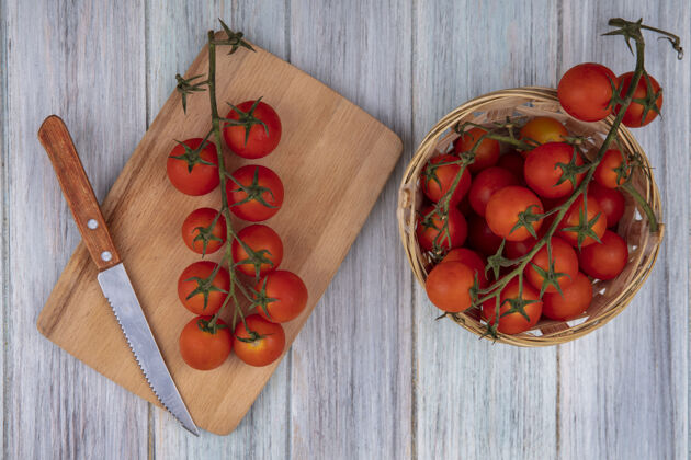 厨房顶部视图成熟的葡萄藤西红柿在一个木制的厨房板与一个灰色木制背景桶上的葡萄藤西红柿刀成熟刀顶部