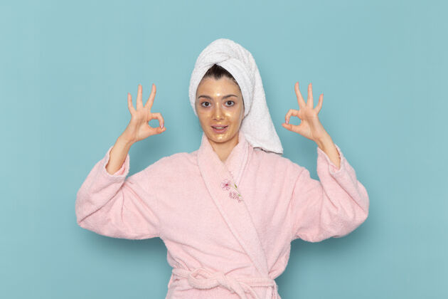 自理正面图身着粉色浴袍的年轻女性在蓝色墙壁上淋浴后清洁美丽干净的水自我护理霜淋浴清洁成人人