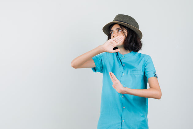 帽子年轻的女士举手为自己辩护 穿着蓝色衬衫 戴着帽子 神情专注优雅乐趣她自己