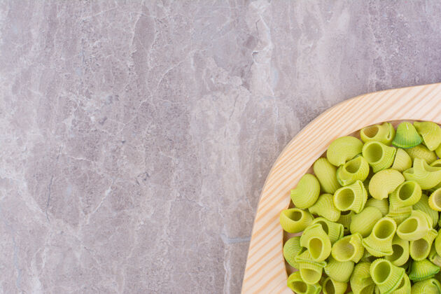 盘子绿色的意大利面放在大理石的木板上极简晚餐生的