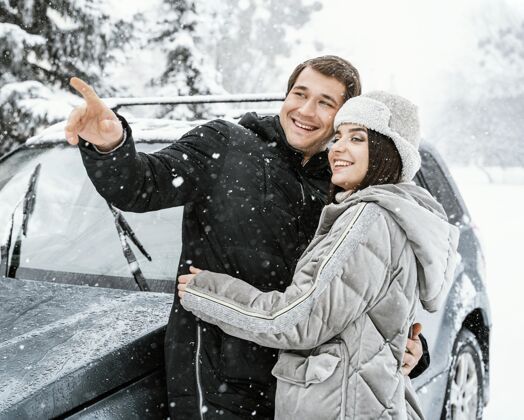 冬天一对微笑的情侣在路上的雪中拥抱男性逗留航行