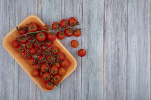 藤蔓新鲜的红色藤蔓西红柿在一个塑料容器上的灰色木制背景与复制空间俯视图复制西红柿灰色
