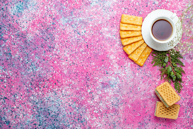 生的浅粉色桌上的一杯茶 上面放着饼干和华夫饼脆的茶墙