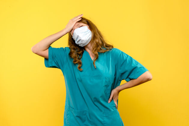 视图正面图年轻女医生在黄色空间的面具上强调服装健康正面