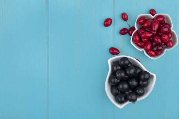 景观顶视图的水果 如山茱萸和树莓在碗和蓝色背景与复制空间碗副本山茱萸