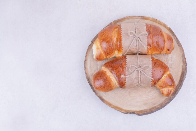 糕点羊角面包被隔离在灰色表面的木盘上奶油美味精致