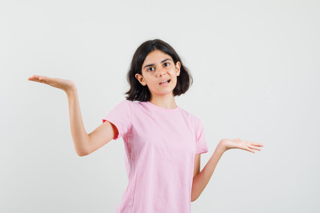 人小女孩穿着粉色t恤做着手势 看起来很困惑前视图青少年肖像手势
