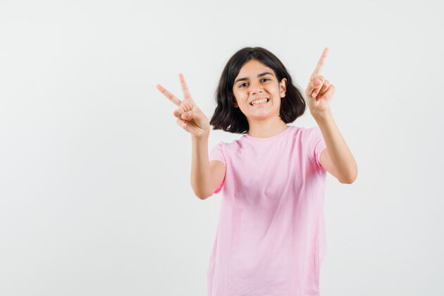 成人小女孩展示了v型标志 穿着粉色t恤向上指着 看起来很快乐 正面视图肖像未成年粉色