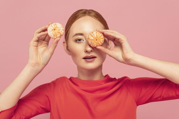 美丽用橘子遮住眼睛的女人营养模特食物