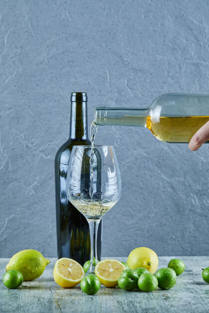 柠檬把白葡萄酒和柠檬倒进杯子里 把一瓶葡萄酒和樱桃李子放在一边饮料奢侈品天然