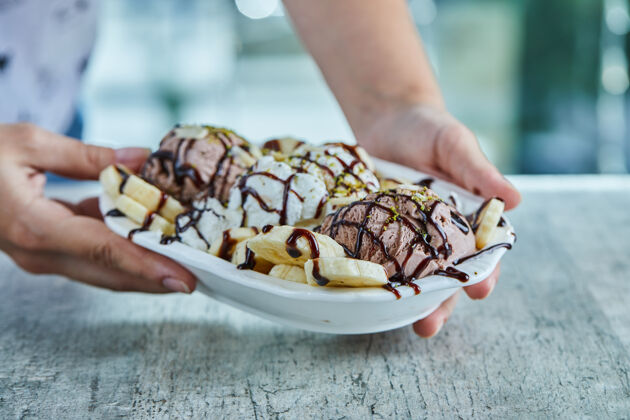 香草手里拿着香蕉冰淇淋 巧克力 洒在白色盘子上冷的甜的手