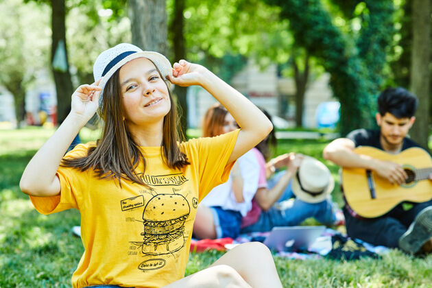 坐着一个年轻的女人和她的朋友在公园里玩 坐在草地上户外人乐趣