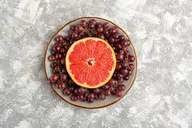 甜白色书桌上有鲜葡萄柚戒指和红葡萄可食用水果戒指食品