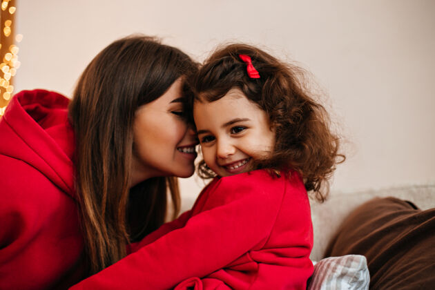 真诚的情感黑发年轻女子亲吻孩子室内拍摄的妈妈和小孩在家微笑房间黑发人表情