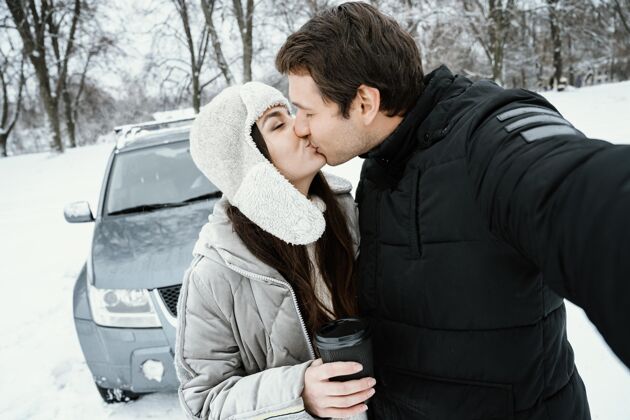 公路旅行在公路旅行中亲吻情侣自拍的正面图车辆自拍冬天