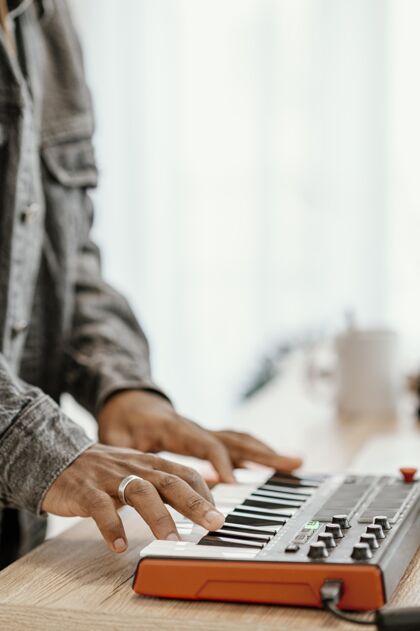乐器男音乐家在家玩电子键盘的侧视图创造者音乐家房子