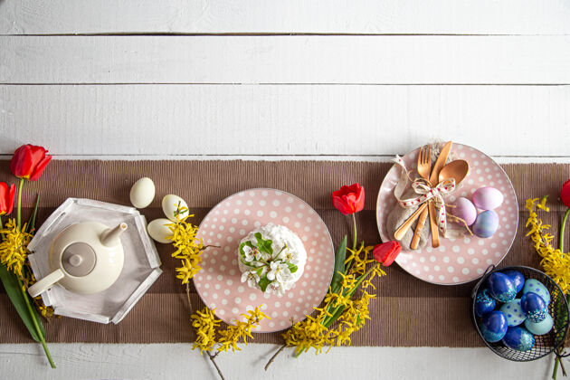 鸡蛋桌上有节日蛋糕 茶壶 彩蛋和鲜花复活节庆典和餐桌布置理念节日设置节日