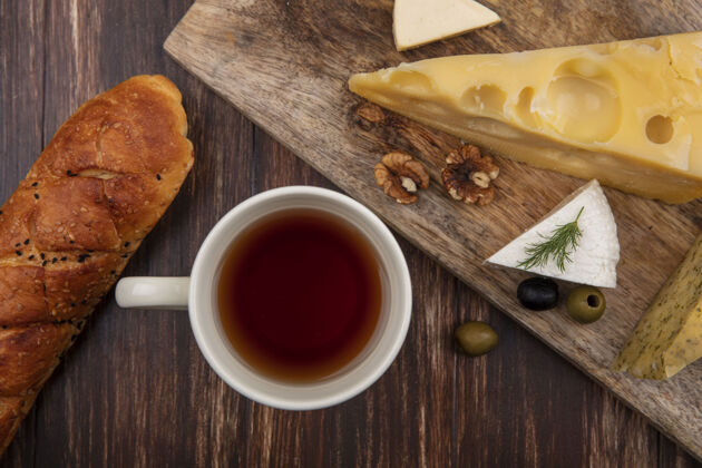 马克杯顶视图一杯茶 在木制背景的木板上放上一片马斯坦奶酪和菲塔奶酪和橄榄风景茶饮料