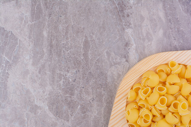传统把生的意大利面放在木盘里 放在大理石表面午餐餐厅食物