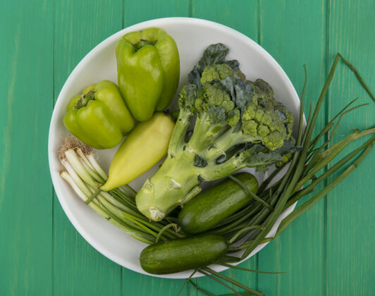 蔬菜在绿色背景的盘子里放上黄瓜 葱和胡椒 俯瞰西兰花西兰花配料洋葱