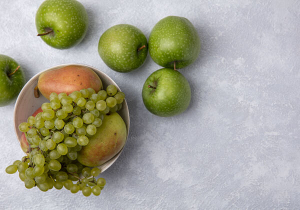 碗顶视图绿色的苹果与绿色的葡萄和梨在一个白色的背景碗梨新鲜白色