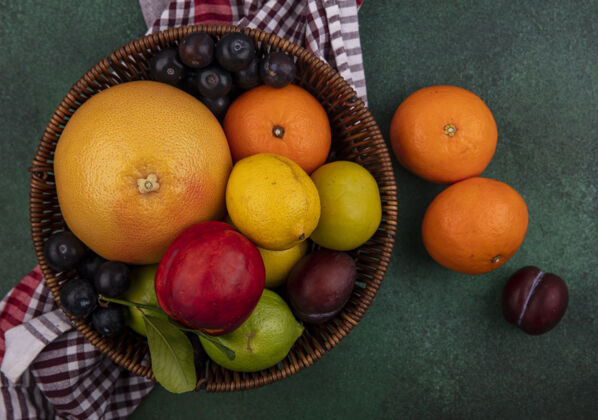 柠檬顶视图桃子樱桃李子橘子柠檬柠檬柠檬柠檬和葡萄柚在一个篮子里与一个格子毛巾绿色背景新鲜视野毛巾