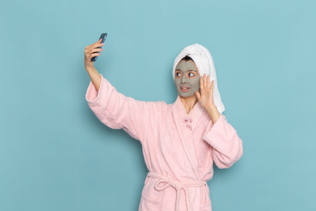 淋浴前视图穿着粉色浴袍的年轻女性淋浴后在蓝色墙壁上自拍美丽水霜自理淋浴前面人男人