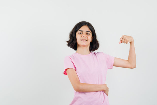 人小女孩穿着粉色t恤展示手臂肌肉 看起来很自信 正面图自信漂亮青少年