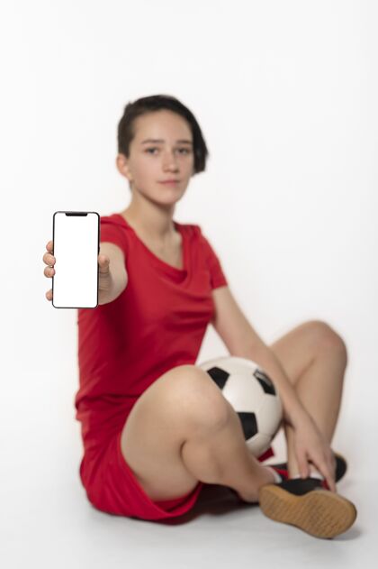 运动拿着足球和电话的女人足球服技术女人