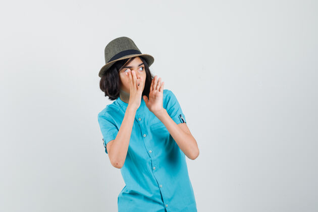 帽子年轻的女士大声叫着一个穿着蓝色衬衫的人 看上去很小心时尚声音室内