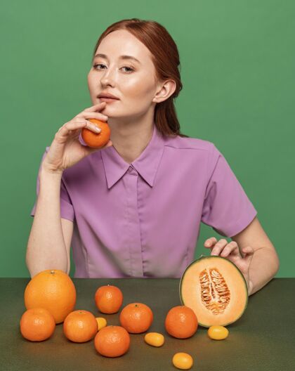 吃美丽的红发女人摆着橘子的姿势美味姿势安排