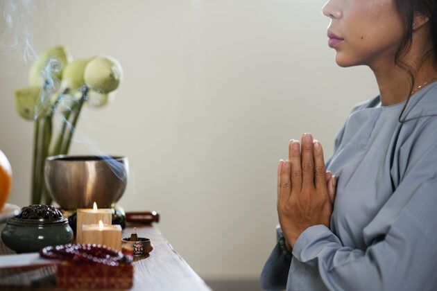 崇拜妇女在蜡烛前祈祷的侧视图亚洲人花神学