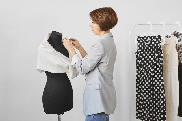 设计师女时装设计师的侧视图与服装形式在工作室工作服装师裁缝个人