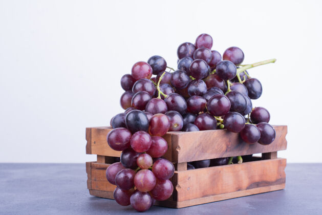 食物红葡萄放在蓝色表面的木制托盘里热带生物水果