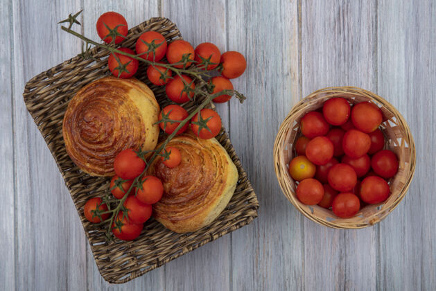 托盘阿塞拜疆传统糕点gogal的顶视图 放在柳条托盘上 桶上放着西红柿 背景是灰色的木制阿塞拜疆西红柿球队