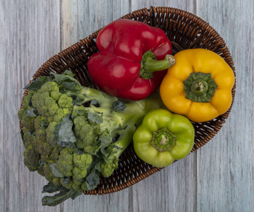 顶部顶视图的蔬菜 如花椰菜和辣椒在篮子里的木制背景篮子食物视野