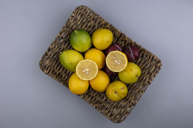 新鲜一桶新鲜柠檬的顶视图 灰色背景上有李子和樱桃李子樱桃李子桶