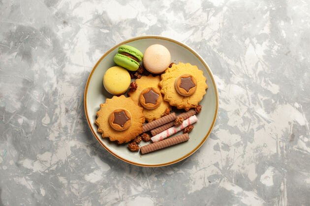 碗俯瞰法国麦卡龙蛋糕和饼干在白色表面饼干饼干糖蛋糕甜馅饼水果盘子顶部