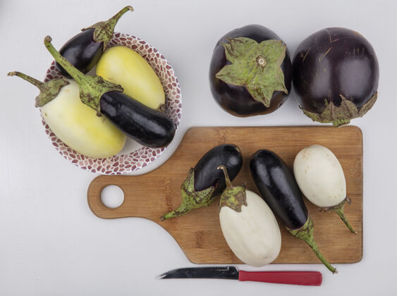 视图顶视图黑白茄子在一个切菜板上用刀和在一个盘子上的白色背景刀切顶部