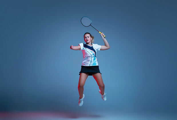 活跃美丽的残疾女子在霓虹灯下的蓝色背景上练习羽毛球包容的人的生活方式 多样性和平等性运动 活动和运动广告空间羽毛球女运动员动作