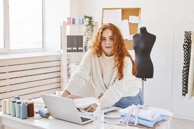 裁缝女时装设计师手持笔记本电脑在工作室工作的正面图工作室商务服装