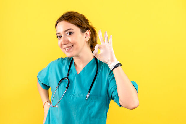 护理黄色墙壁上的女兽医摆姿势微笑的正面图护士药人