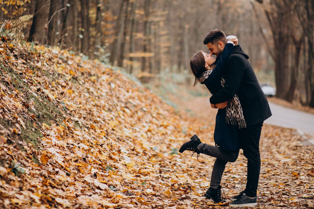 调情一对年轻夫妇在秋天的公园里散步快乐的女人公园浪漫