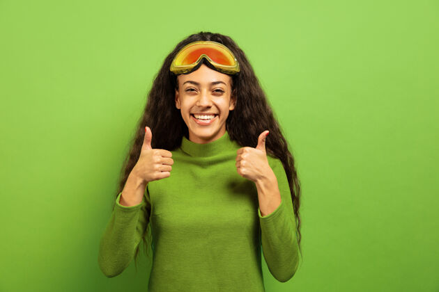 面具以绿色工作室为背景 黑色皮肤的非洲裔年轻女子的滑雪面具肖像人类情感的概念 面部表情 销售 广告 冬季运动和假日微笑 竖起大拇指减肥肖像女性