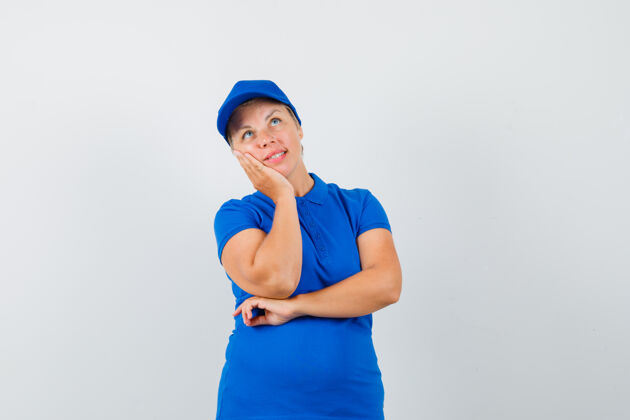 蓝色一个成熟的女人 穿着蓝色t恤 面颊靠在凸起的手掌上 看上去充满希望手掌信心女人