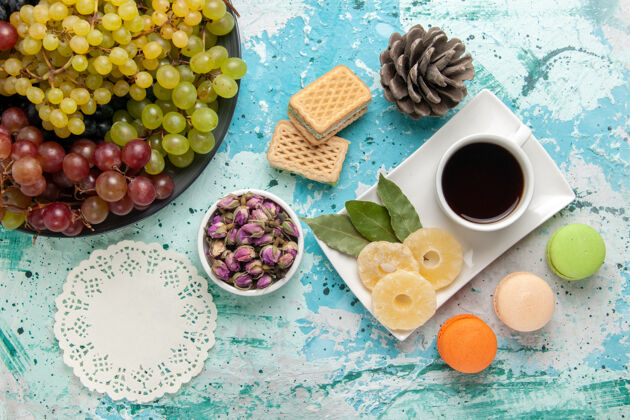 颜色顶视图新鲜的彩色葡萄与一杯茶马卡龙和华夫饼的蓝色背景水果浆果新鲜醇厚的果汁酒早餐晚餐景观