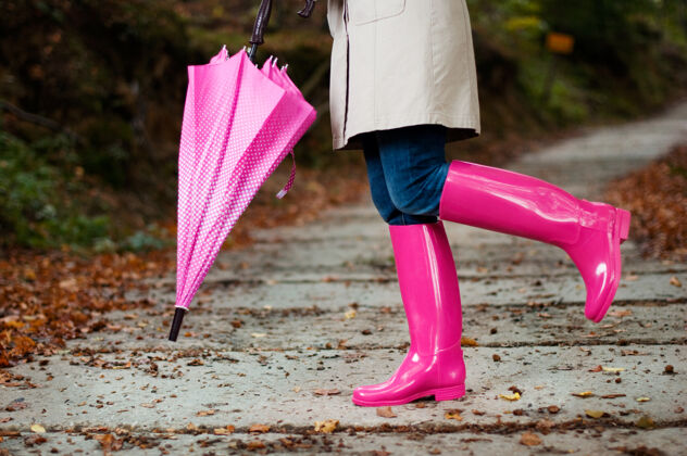 散步带伞穿胶靴的女人站穿树叶